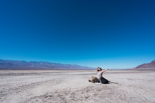 USA, California, Death Valley, man sitting on ground in the desert