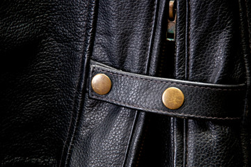 Detail of old leather motorcycle jacket focusing on zipper and waist strap.