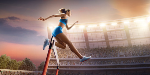 Fototapeta na wymiar Female Track and field athlete jumps over the barrier at the running track in professional stadium