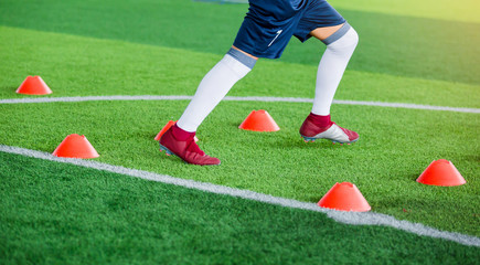 Soccer player Jogging and jump between cone markers on green artificial turf for soccer training