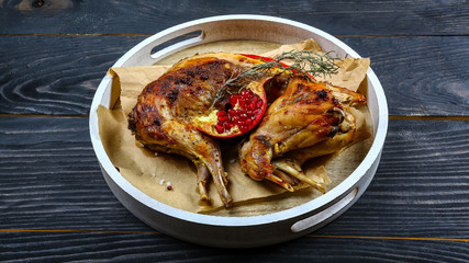 roasted rabbit with pomegranate and rosemary on a paper on the old table. horizontal view from above, rustic style