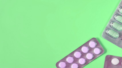 Blisters of different pills on green background. Copy space for text