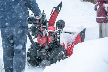 A man cleans snow from sidewalks with snowblower in Bavaria Germany.