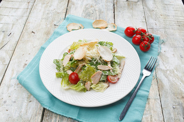 Caesar salad with chicken and greens on wooden table