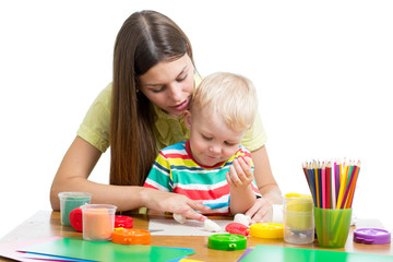 Young woman playing with her boy with plasticine isolated on white background