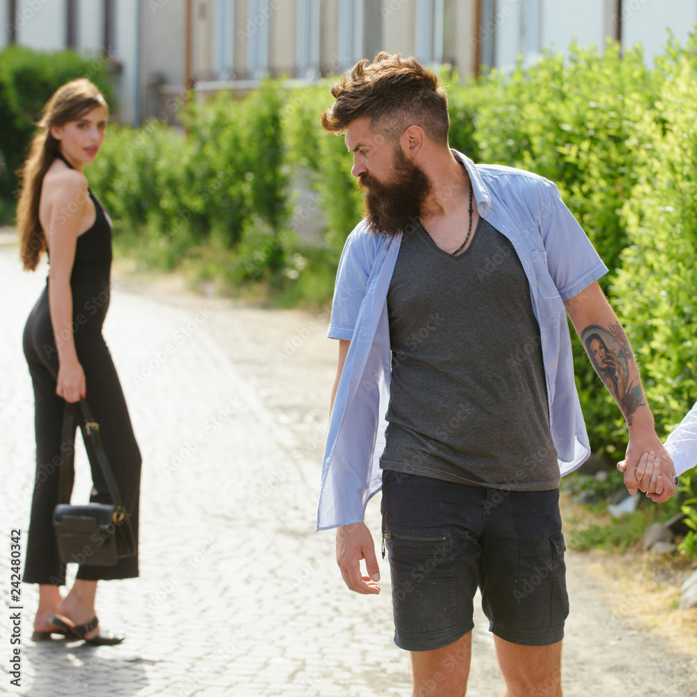 Wall mural feeling flirtatious. bearded man and cute woman walk on street. hipster look back at pretty woman. c