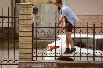 Active and energetic. Hipster climber. Hipster getting over fence. Bearded man climbing in trendy...