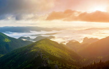 Fantastic view of mountain valley covered with low white puffy like snow clouds stretching to foggy...