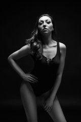 Obraz na płótnie Canvas Sensual female model posing in light stream from above. Black and white fashion lingerie photo.
