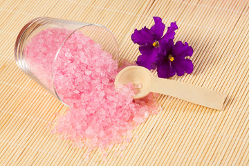 Obraz na płótnie Canvas pink sea salt for bath and spoon on bamboo mat