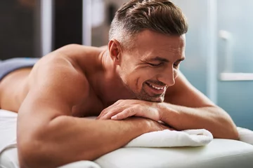 Zelfklevend Fotobehang Badkamer Handsome young man with closed eyes lying on massage table  © Yakobchuk Olena