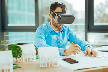 Attentive engineer smiling while working with virtual reality glasses