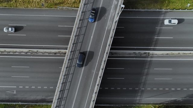 Static aerial drone shot of bridge diagonally cross busy freeway or highway. Neat and minimalistic image of traffic of commuters leave and enter big city. Suburban neighbourhoods and vehicle culture