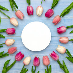 Wedding mockup with round white paper and pink tulip flowers on blue table top view. Beautiful floral pattern. Flat lay style.