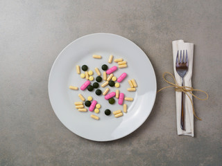 Bunte Tabletten auf einem weißen Teller, Gesunde Ernährung, Vitamine