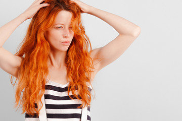 Obraz premium Red-haired girl ran her fingers through her hair and squinted