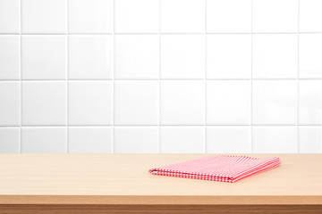 Empty wooden table with tablecloth over white tile wall. Background for advertise product.