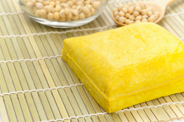 Yellow tofu loaf on bamboo sheet.