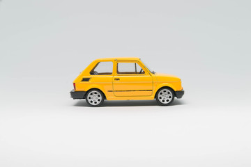 Mały fiat 126p auto zabawka koloru żółtego bokiem - obrazy, fototapety, plakaty