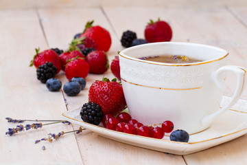 Herbal tea with lavender and mint, fresh strawberries, blackberries and blueberries on a white wooden table. Berry tea with fresh strawberry, blackberry.