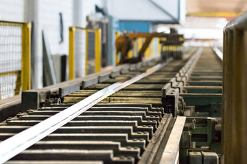 An aluminium profile on the puller stage on an extrusion profile roller runout table. - obrazy, fototapety, plakaty