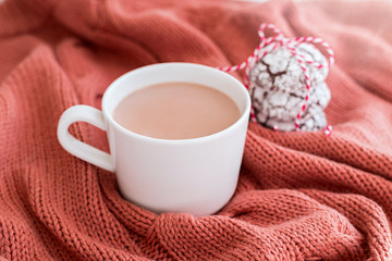 Obraz na płótnie Canvas Cup of coffee with milk and chocolate cookies on warm knitted coral blanket.