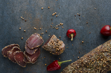 Top view of dried meat with red pepper on dark table