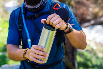 Hiker opening thermos on a hiking trip close up