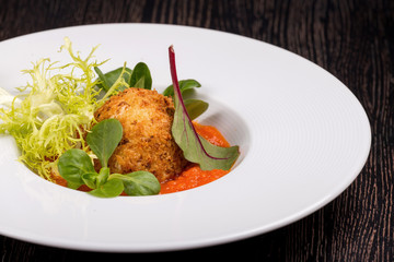 Arancini with marinar sauce and herbs on a wooden background.
