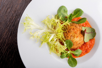Arancini with marinar sauce and herbs on a wooden background.