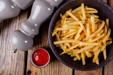 French fries with sauce and pepper on a wooden background.