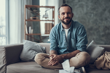 Cheerful man sitting with his arms crossed and smiling