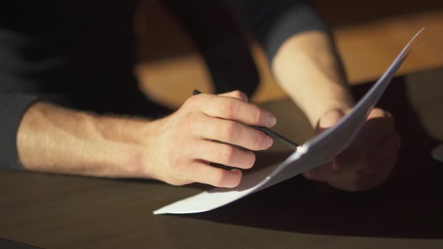 Male hands making paperwork with writing amendments in documents close up. A businessman studies graphics and makes planned adjustments for the future.
