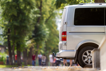 Side view detail of white passenger medium size luxury minibus van parked on summer city street...