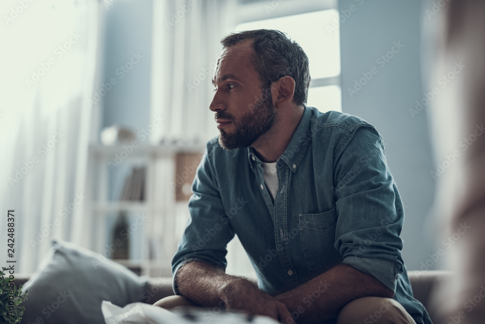 Wall mural Waist up of bearded man thoughtfully looking away