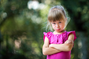 Portrait of pretty funny moody unhappy young blond child girl in pink sleeveless dress feeling...