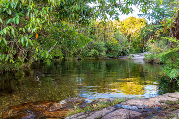 Small lake and stream with transparent water between the rainforest vegetation in Carrancas, Minas Gerais, Brazil