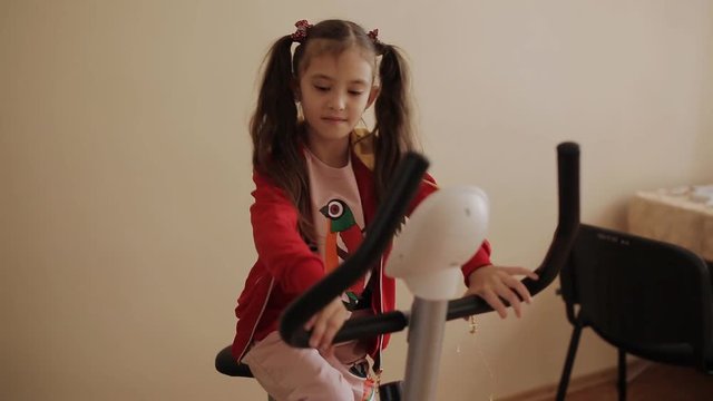 The little girl in the children's gym is doing on the treadmill.