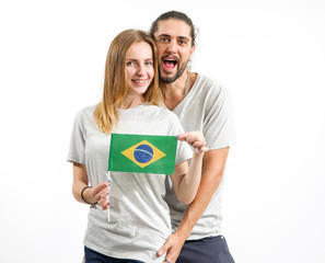 Fototapeta premium Happy couple in gray t-shirts with the flag of Brazil, isolated on white background. Fun people, man and woman.