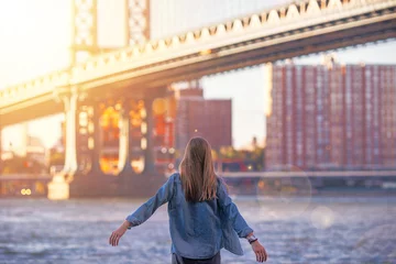 Fotobehang Woman standing near the river in New York, Brooklyn Bridge. - Image © Serhiy Hipskyy