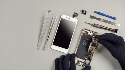 Technician or engineer disassembling components broken smartphone and take off logic board for...
