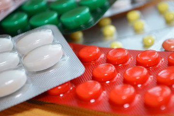 Yellow, white, red, green medical tablets in pack, tablets packed in blisters. Healthcare and medical concept closeup