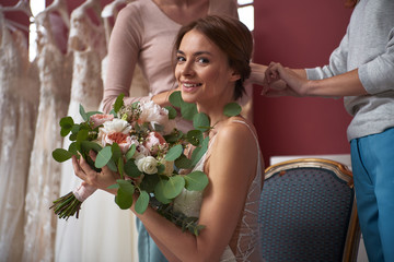 Tidying hairs of happy bride in wedding dress