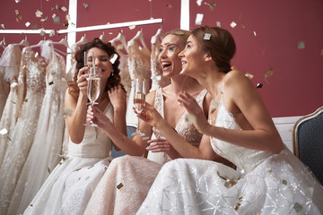 Waist up of cheerful brides with champagne glasses