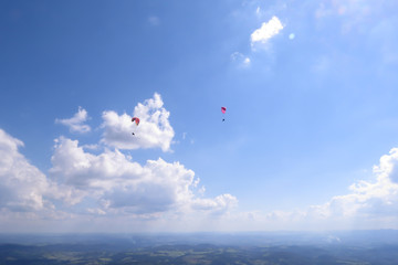 Paraglider flying on colored parachute in blue clear sky at a bright sunny summer day. Active lifestyle, extreme hobbies