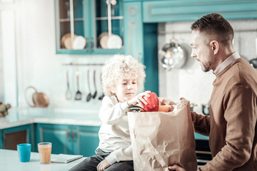 Attentive boy taking pepper from paper bag