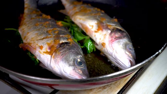 A chef cooks a Sea bass in frying pan.cooking concept. 4k, seafood