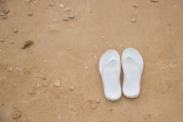 Fototapeta na wymiar White slippers on golden sand