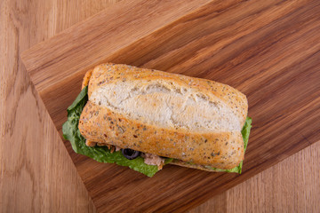 Sandwich from gray bread with fish and lettuce leaves