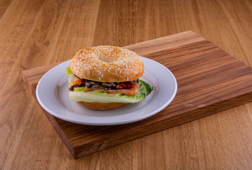 Red fish, dried tomatoes sandwich on a plate on a wooden board